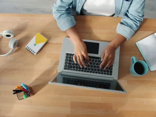 Top-down view of a person working on a laptop at a neat desk with accessories.